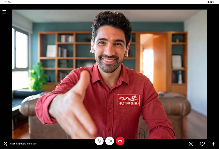 Captura de pantalla de una videollamada con un asesor de viajes sonriente de Destino China ofreciendo un saludo de mano.